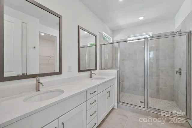 a bathroom with double sink shower and a mirror