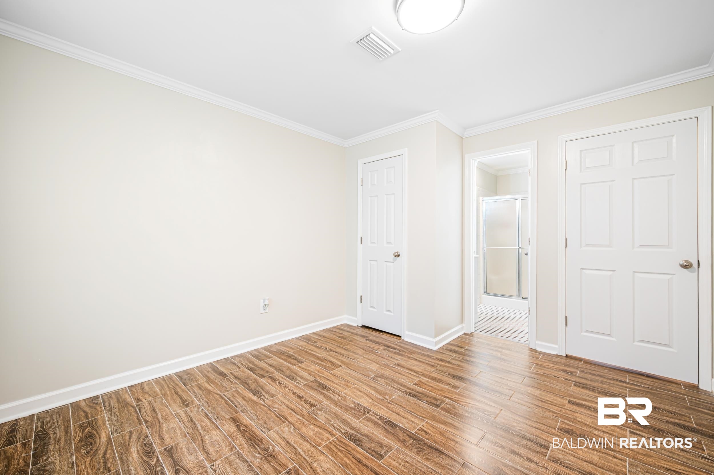 1605 Collier Avenue Bay Minette, AL 36507 - Photo 21 of 36 Unfurnished bedroom featuring wood finished floors, crown molding, a closet, and connected bathroom