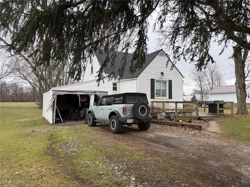 View of front of property featuring a front yard, a deck, and roof with shingles