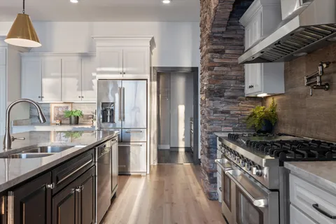 a kitchen with stainless steel appliances granite countertop a stove a sink dishwasher a refrigerator and cabinets with wooden floor