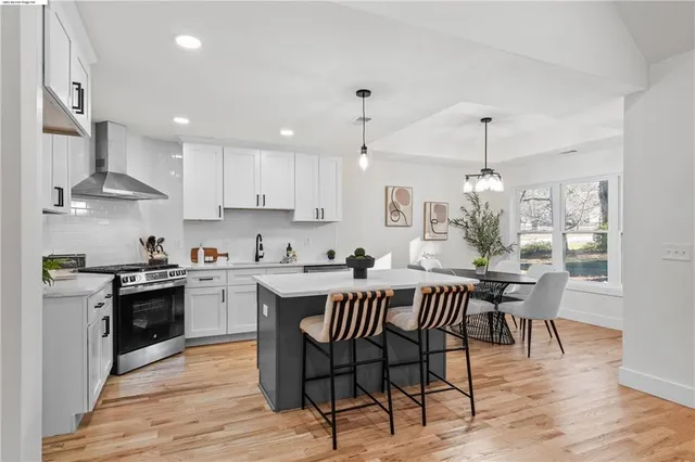 a kitchen with stainless steel appliances granite countertop a sink a stove a refrigerator and white cabinets with wooden floor