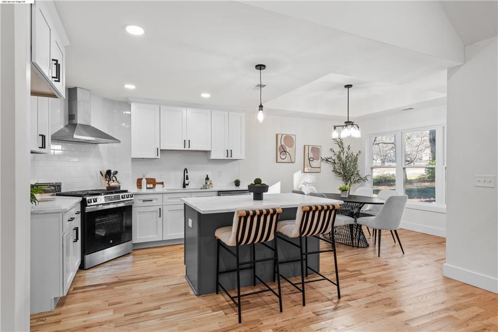 1883 Bennett Ridge Southwest Snellville, GA 30078 - Photo 12 of 56 a kitchen with stainless steel appliances a dining table chairs stove and white cabinets