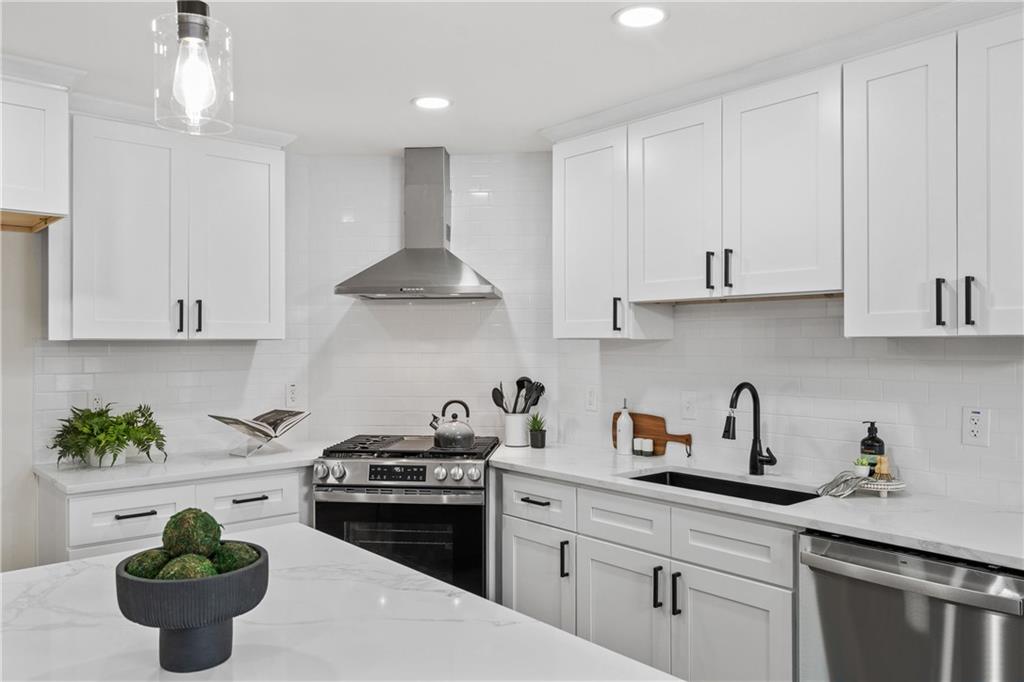1883 Bennett Ridge Southwest Snellville, GA 30078 - Photo 14 of 56 a kitchen with stainless steel appliances a white sink a stove a refrigerator and cabinets