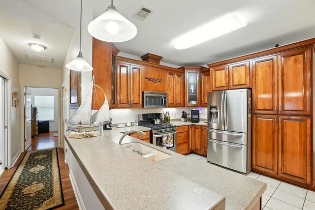 a kitchen with stainless steel appliances granite countertop a refrigerator a sink dishwasher a stove and a dining table with wooden floor