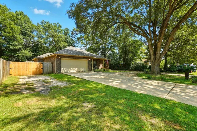 a backyard of a house with large trees and wooden fence