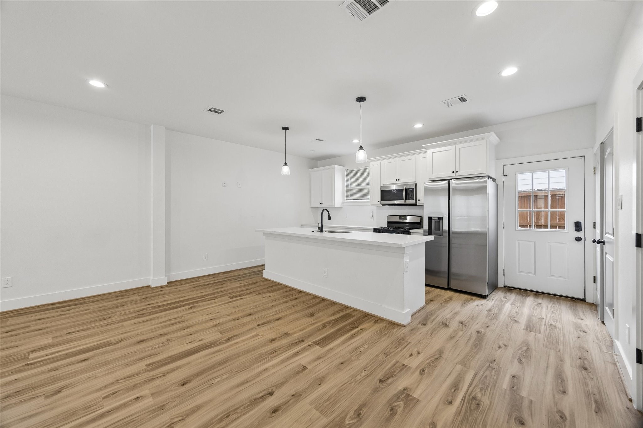 2749 Redrock Street, Unit B Houston, TX 77088 - Photo 7 of 24 A large quartz surfaced island is the statement in the open kitchen with a door on the right leading to the backyard.