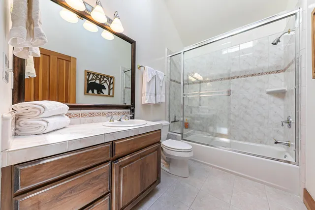 a bathroom with a granite countertop sink a toilet and shower