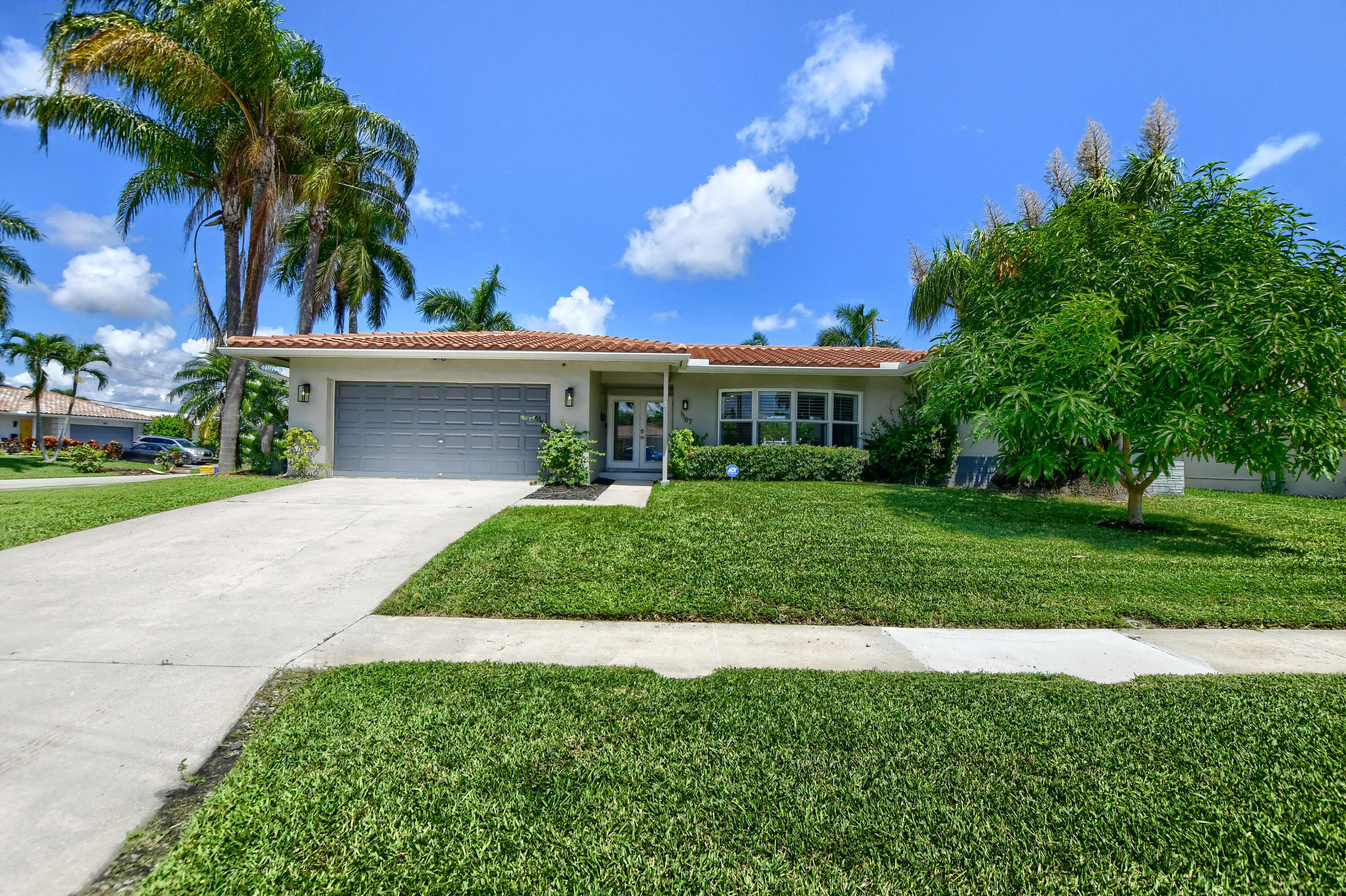 1167 Southwest 13th Drive Boca Raton, FL 33486 - Photo 1 of 41 a front view of a house with a garden