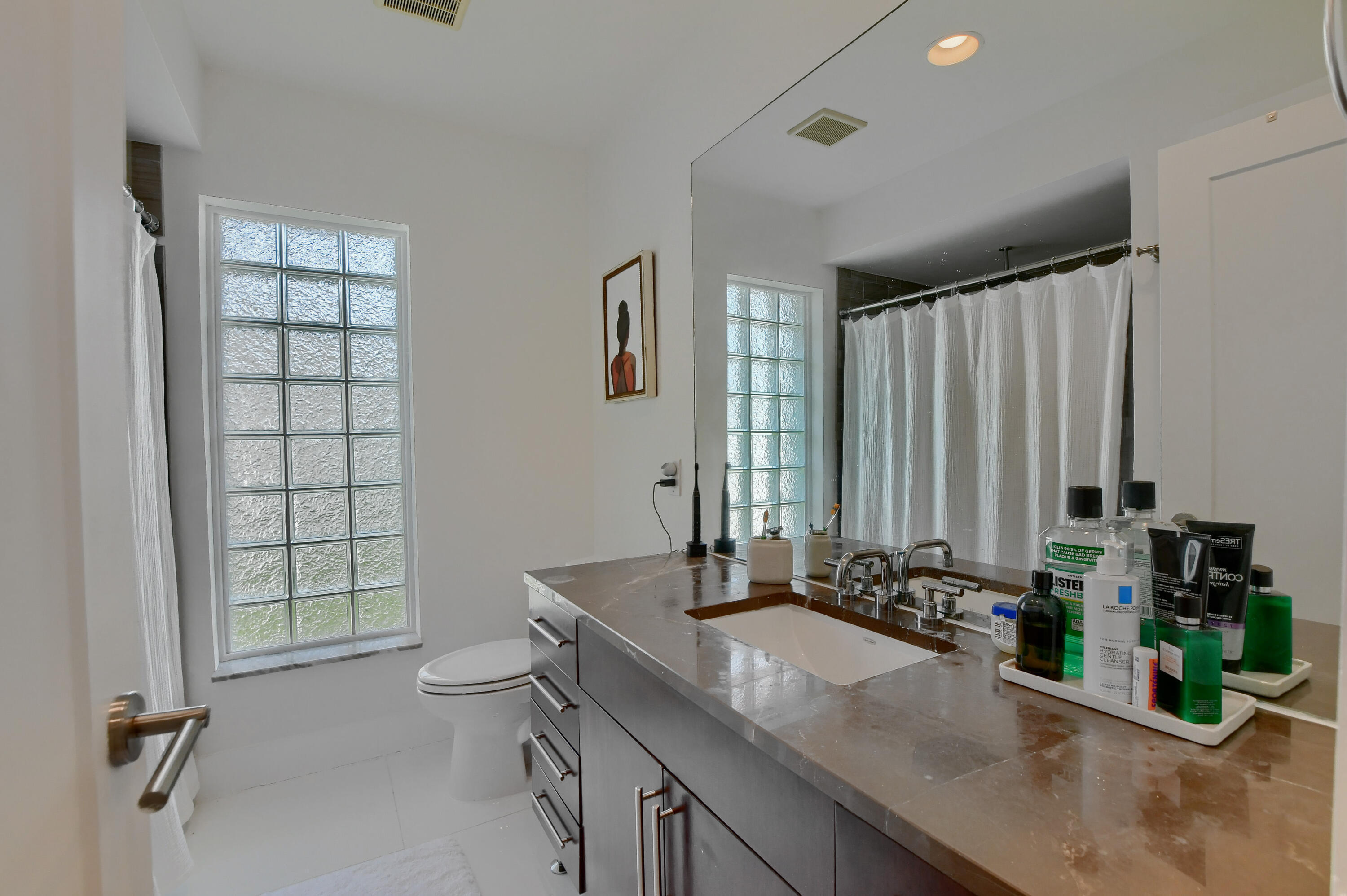 1167 Southwest 13th Drive Boca Raton, FL 33486 - Photo 20 of 41 a bathroom with a granite countertop sink a toilet a mirror and shower