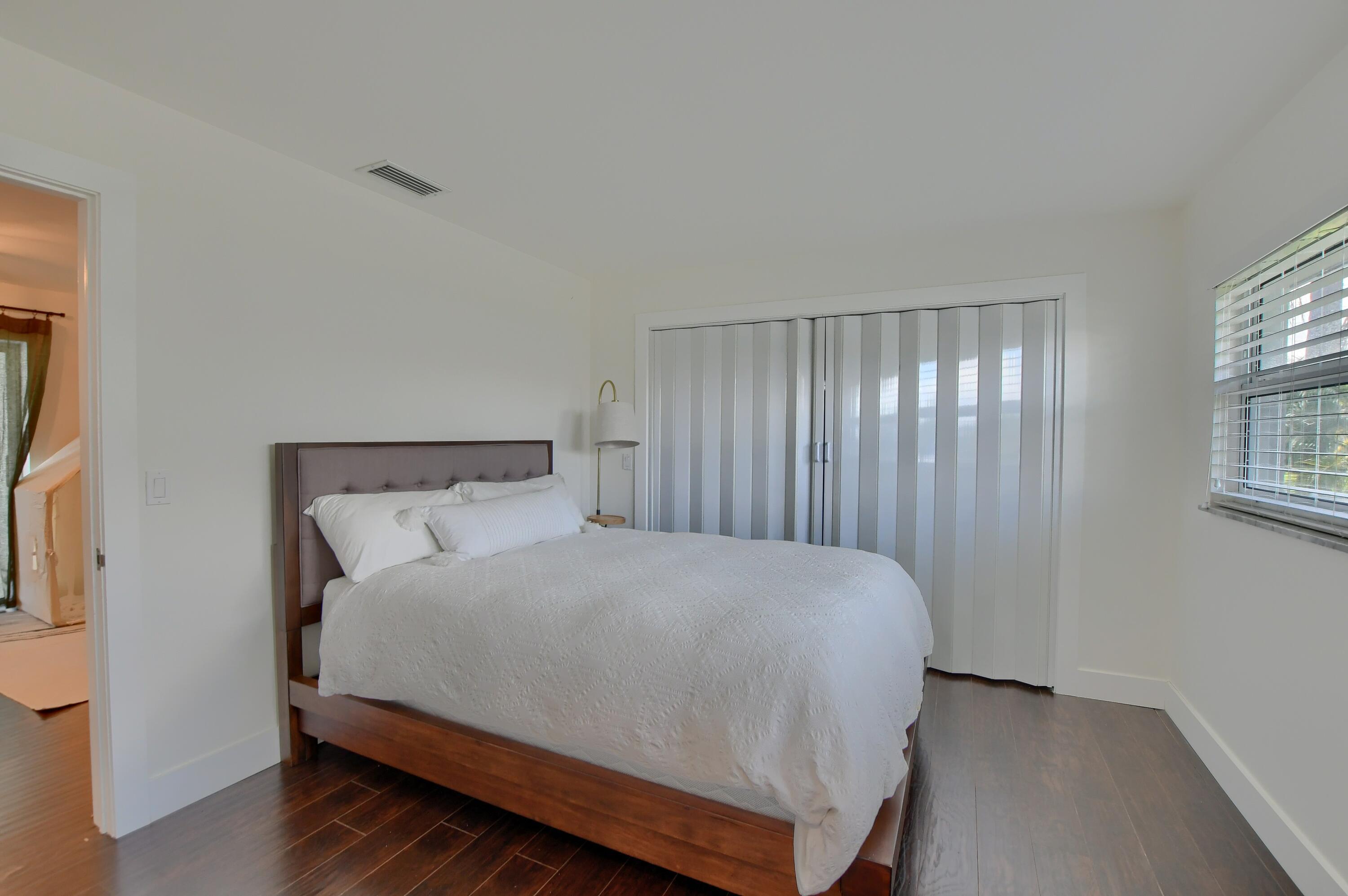 1167 Southwest 13th Drive Boca Raton, FL 33486 - Photo 26 of 41 a large bed sitting in a bedroom next to a window and chandelier
