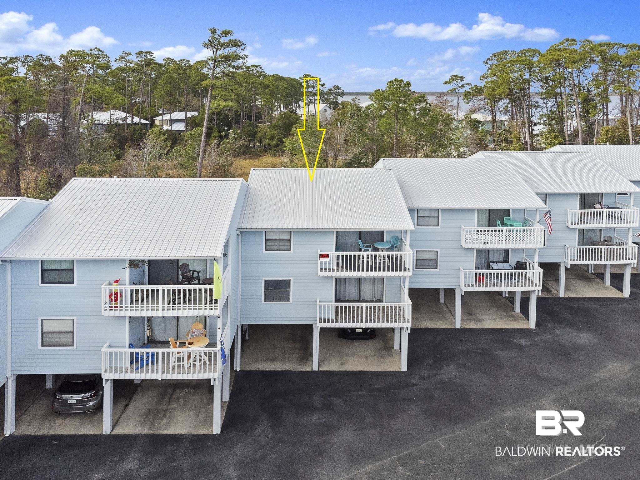 25861 Canal Road, Unit 77 Orange Beach, AL 36561 - Photo 39 of 48 Back of house featuring a metal roof, a balcony, and view of wooded area