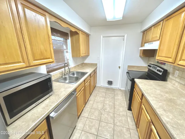 an empty room with a chandelier fan and windows