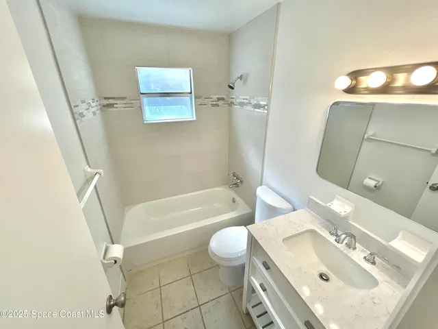 a bathroom with a granite countertop sink a toilet a mirror and shower