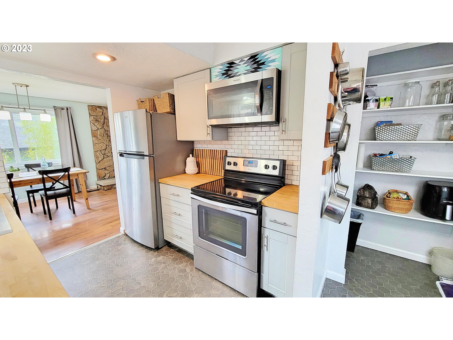 268 South 68th Place Springfield, OR 97478 - Photo 3 of 22 a kitchen with stainless steel appliances kitchen island granite countertop a refrigerator a stove a sink a dining table and chairs with wooden floor