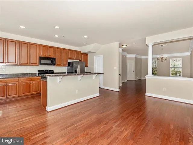 a kitchen with stainless steel appliances granite countertop a stove top oven a sink dishwasher and a microwave oven on the wooden floor