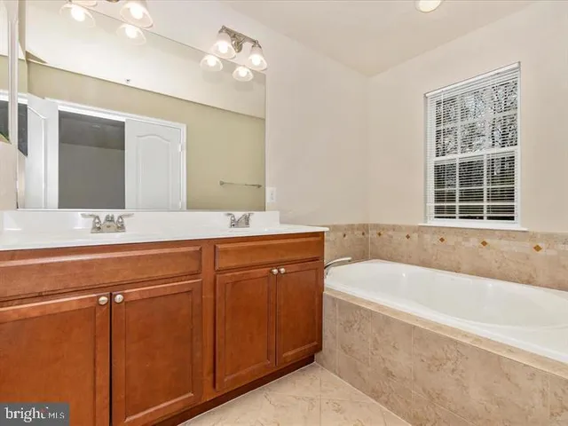 a spacious bathroom with a tub sink and mirror