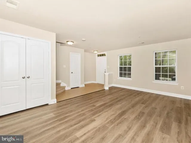 a view of an empty room with wooden floor and windows
