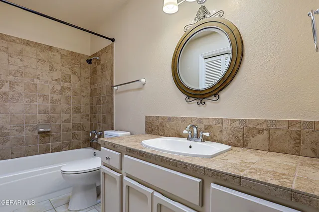 a bathroom with a granite countertop toilet a sink and a mirror