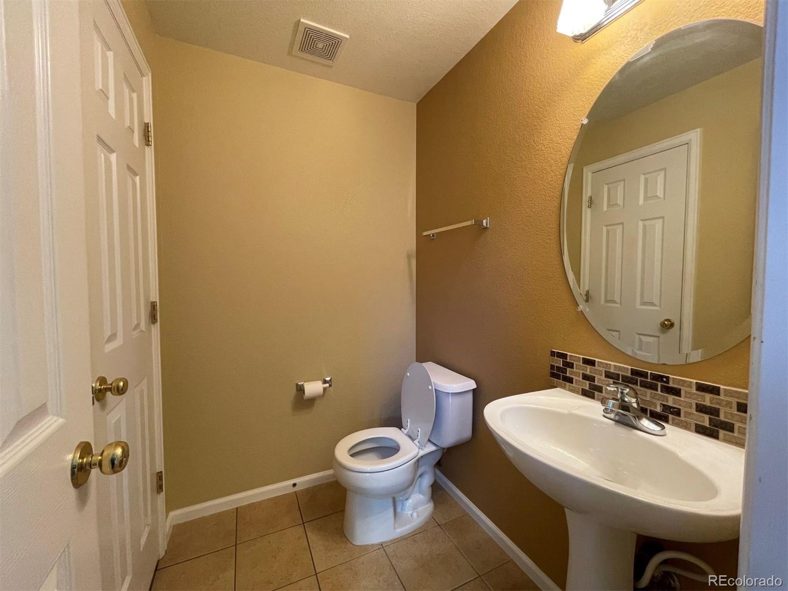 10838 Towerbridge Road Highlands Ranch, CO 80130 - Photo 7 of 26 a bathroom with a toilet a sink and mirror