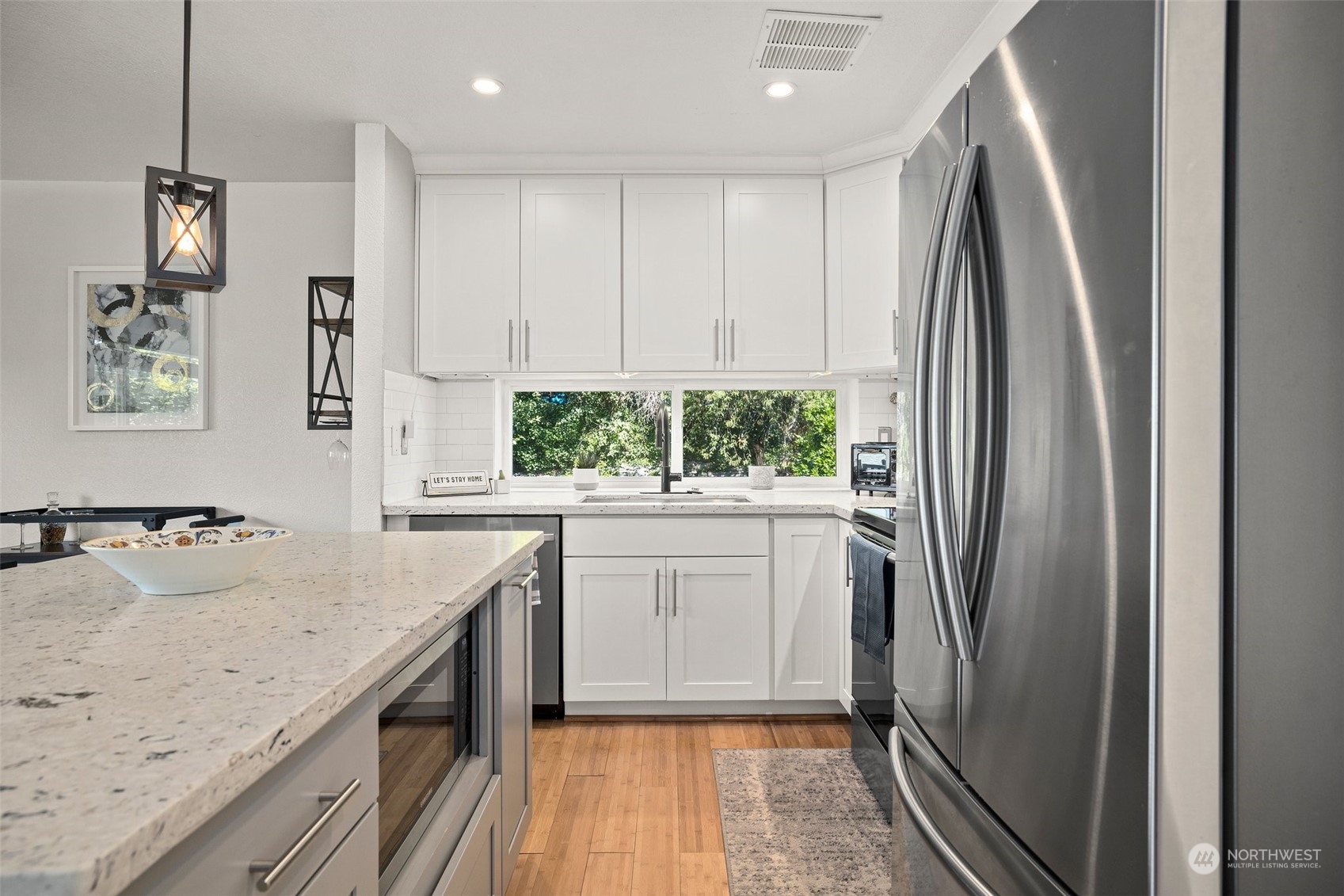 7222 16th Avenue Southwest Seattle, WA 98106 - Photo 11 of 31 a kitchen with stainless steel appliances granite countertop a refrigerator a sink a stove and white cabinets with wooden floor