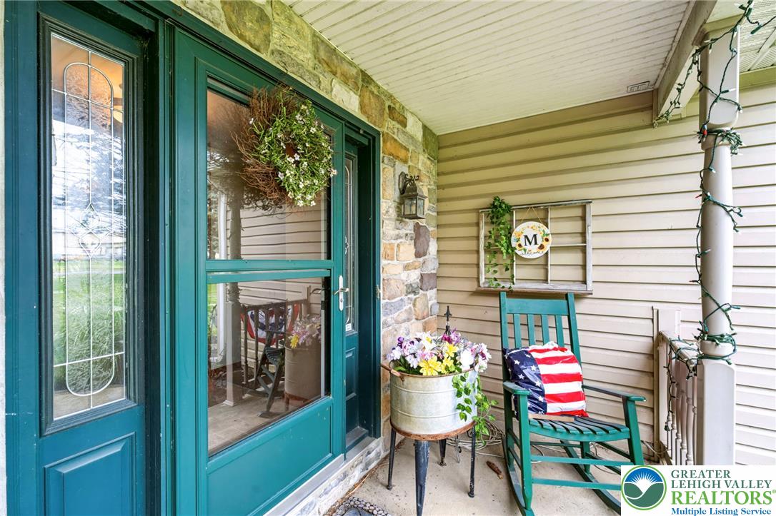 A welcoming front porch features stone accents and a cheerful green rocking chair.