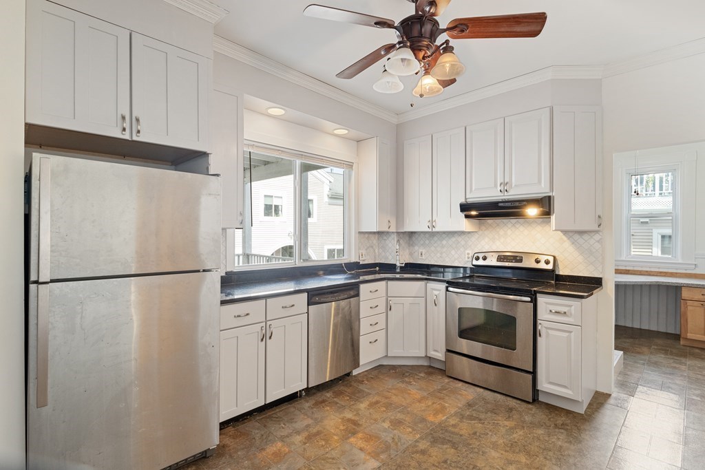 a white kitchen with stainless steel appliances granite countertop a stove a refrigerator and a sink