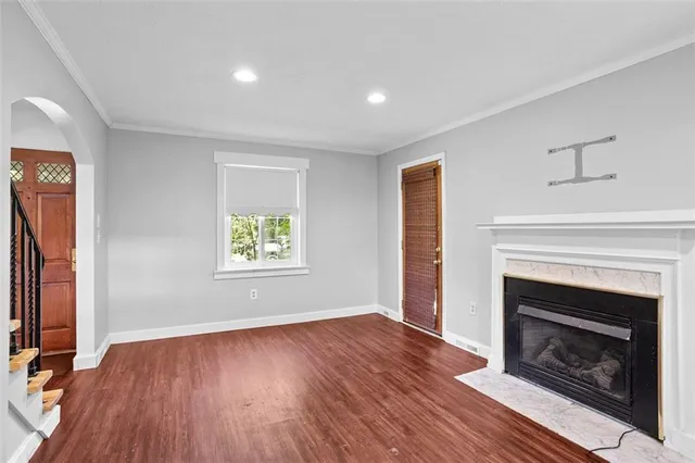 a view of an empty room with wooden floor fireplace and a window