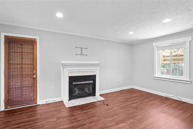an empty room with wooden floor fireplace and windows