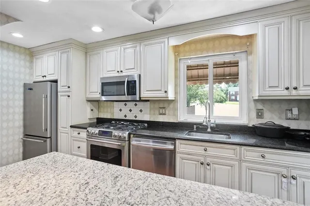 a kitchen with granite countertop a sink stainless steel appliances and cabinets