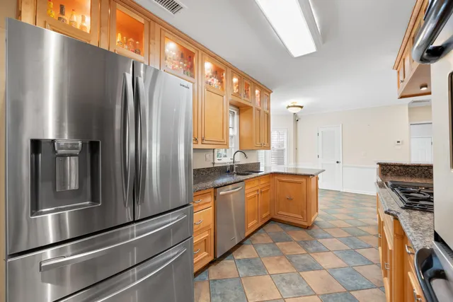 a kitchen with stainless steel appliances granite countertop a refrigerator a stove and a sink
