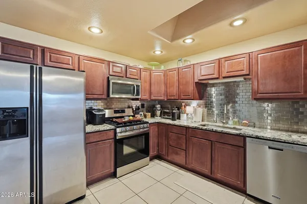 a kitchen with stainless steel appliances granite countertop a refrigerator a sink a stove a microwave and island