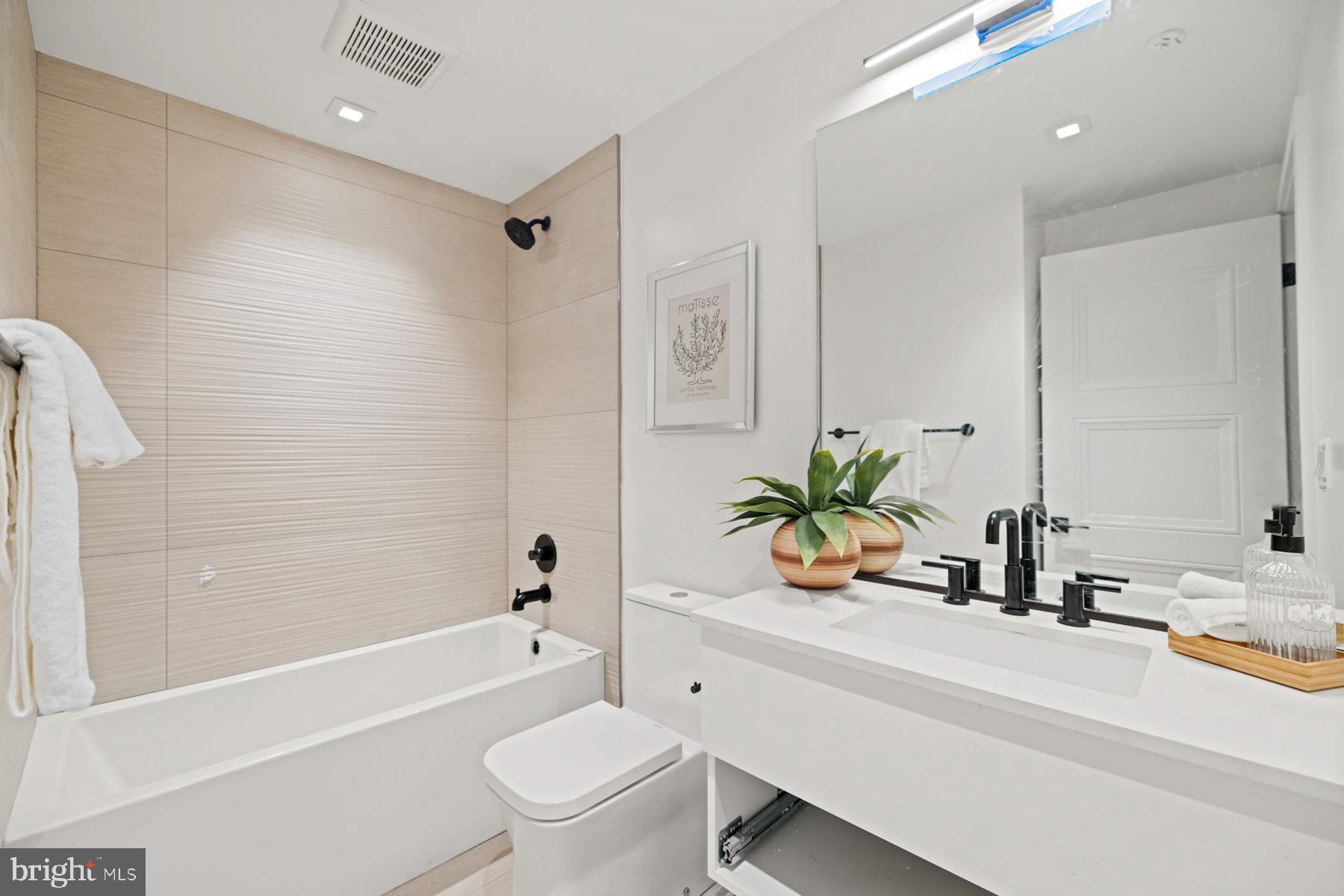 1525 P Street Northwest, Unit 1 Washington, DC 20005 - Photo 6 of 13 a bathroom with a granite countertop sink a toilet a mirror a bathtub and shower