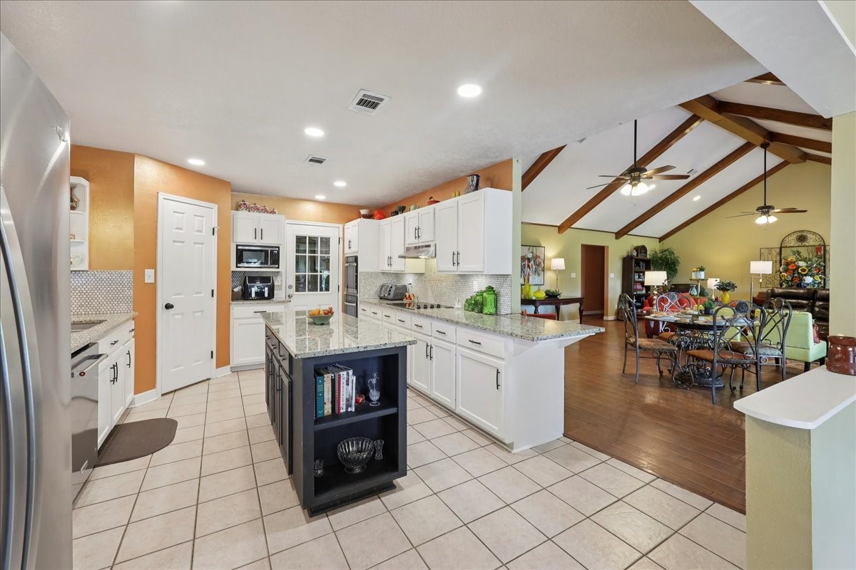 7769 Moonglow Circle Lumberton, TX 77657 - Photo 10 of 35 a kitchen with stainless steel appliances kitchen island granite countertop a refrigerator a stove a sink and a dining table with wooden floor