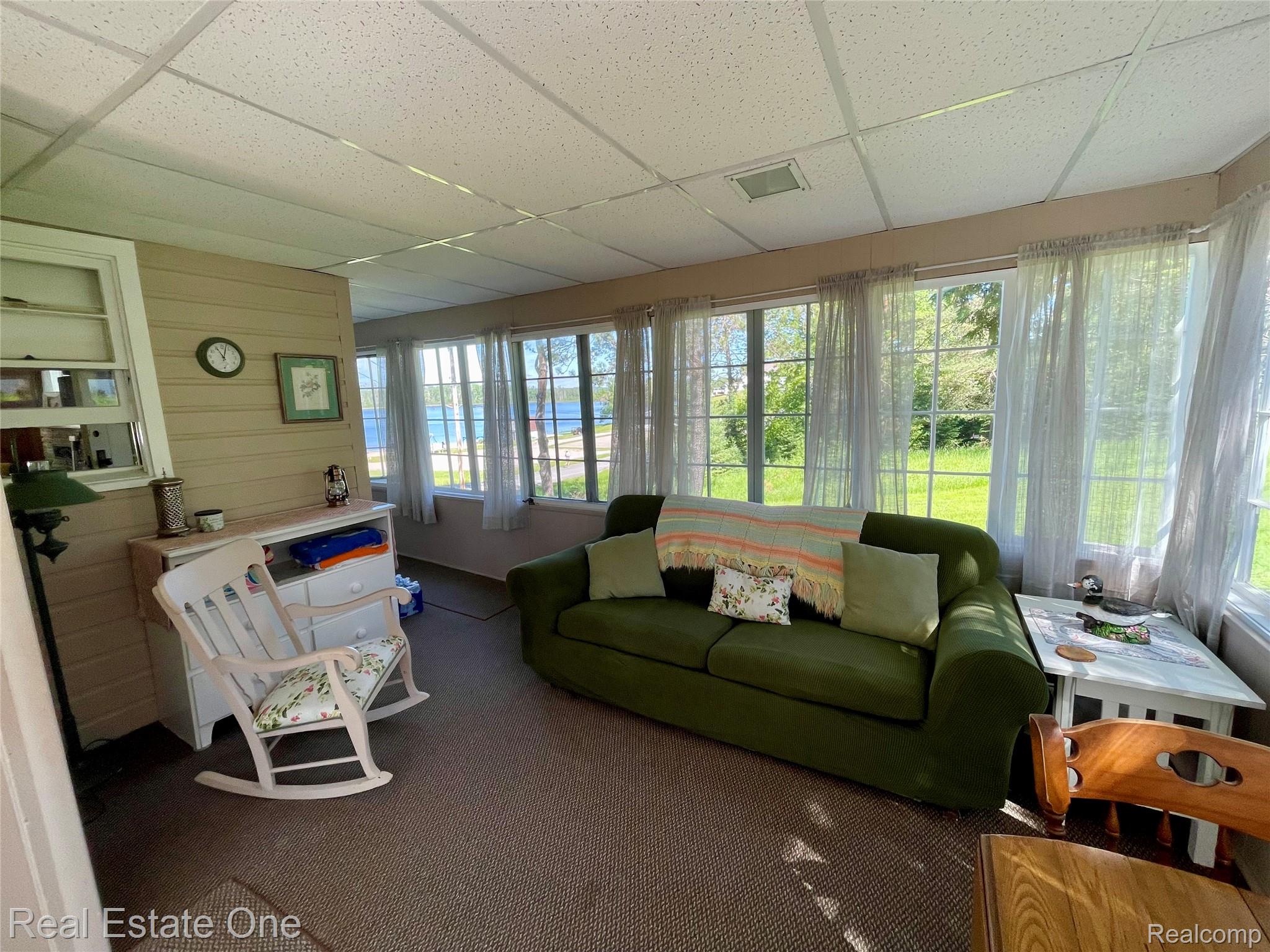 4160 Hawk Road Lincoln, MI 48742 - Photo 23 of 48 Sunroom featuring extensive window-lined walls, a drop ceiling, horizontal paneling, and carpeted flooring