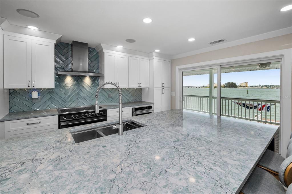 804 Bay Point Drive Madeira Beach, FL 33708 - Photo 65 of 100 a kitchen with stainless steel appliances granite countertop a stove a sink and a granite counter tops with white cabinets