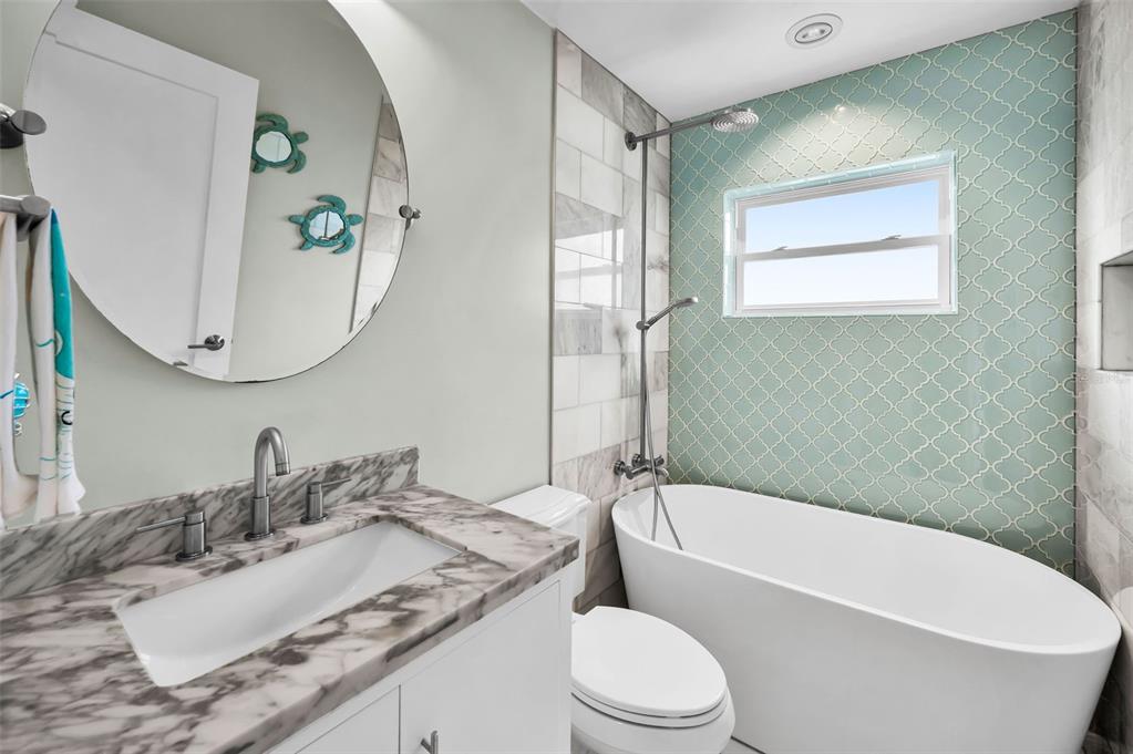 804 Bay Point Drive Madeira Beach, FL 33708 - Photo 99 of 100 a bathroom with a granite countertop bathtub sink vanity mirror and toilet