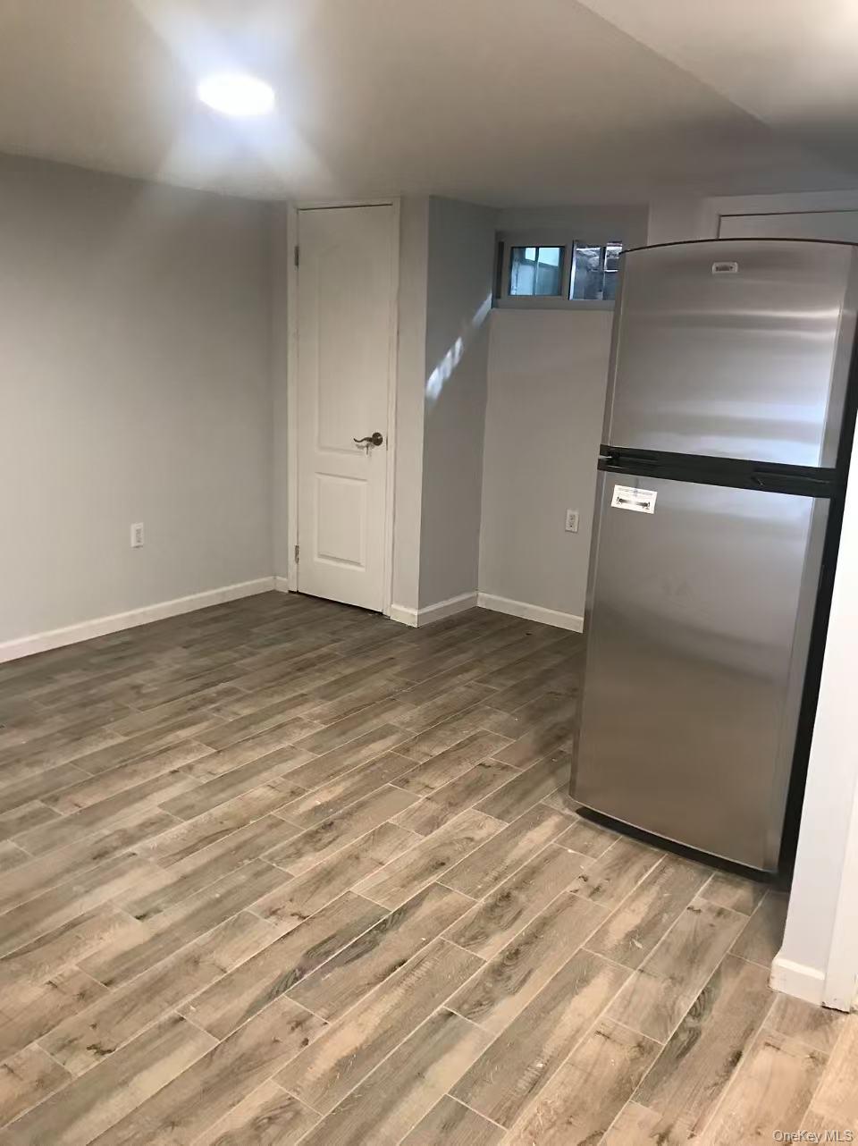 148-49 58th Road Queens, NY 11355 - Photo 6 of 10 an empty room with wooden floor and entrance