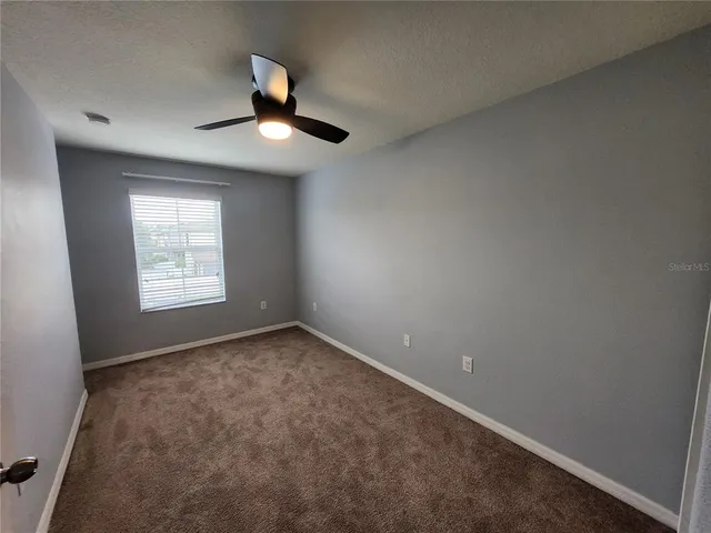 an empty room with a ceiling fan and a window