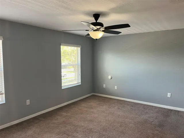 an empty room with windows and fan