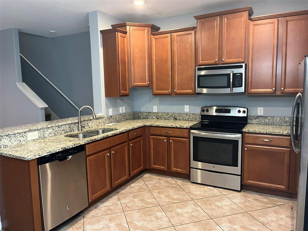 1242 Acadia Harbor Place Brandon, FL 33511 - Photo 3 of 28 a kitchen with stainless steel appliances granite countertop a stove a sink and a microwave