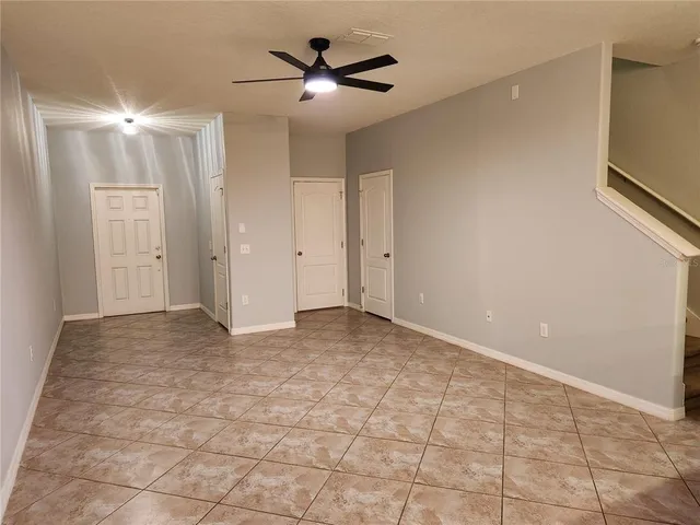 a view of an empty room and chandelier fan