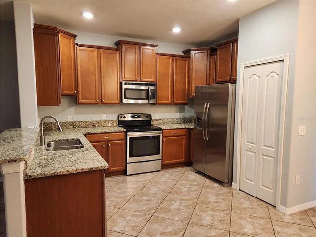 a kitchen with stainless steel appliances granite countertop a refrigerator sink and stove