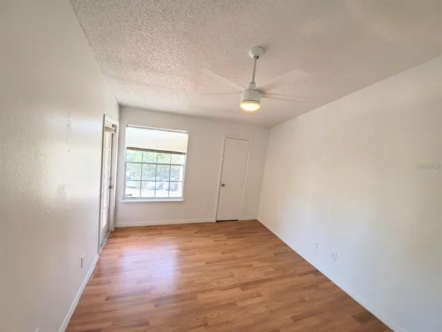 an empty room with wooden floor fan and windows