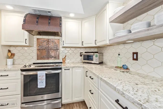 a kitchen with stainless steel appliances granite countertop a stove a sink and a microwave