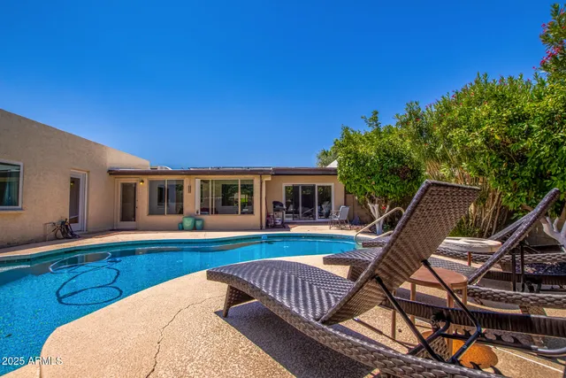 a swimming pool with outdoor seating and potted plants