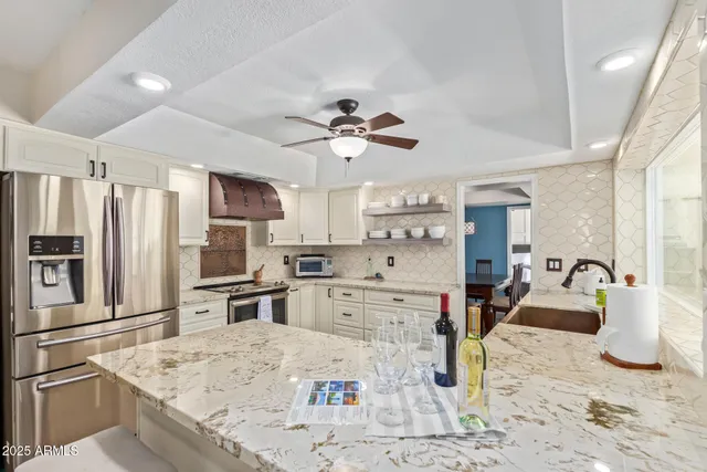 a kitchen with stainless steel appliances kitchen island granite countertop a refrigerator stove and sink