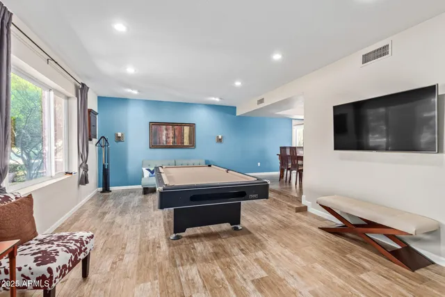a living room with a flat screen tv on dresser and a table