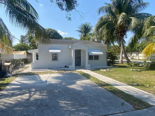a view of a house with a yard and palm trees
