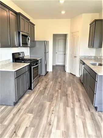 a large kitchen with stainless steel appliances granite countertop a stove a sink and a microwave