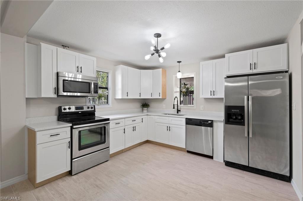 17397 Lee Road Fort Myers, FL 33967 - Photo 3 of 22 a kitchen with granite countertop a refrigerator stove a sink and dishwasher with wooden floor